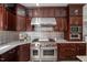 A traditional kitchen with stainless steel appliances, dark wooden cabinets, and a decorative backsplash at 817 Highwater Pl, Fuquay Varina, NC 27526