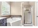 Bathroom featuring a soaking tub with decorative tile accents and a glass-enclosed shower at 8600 Clivedon Dr, Raleigh, NC 27615