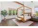 Airy bedroom with hardwood floors, four-poster bed, sitting stools, and natural light from large windows at 904 Harrison Ridge Rd, Wake Forest, NC 27587