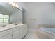 Bathroom featuring double sinks, a vanity, a soaking tub, and neutral tile flooring at 9508 Vira Dr, Raleigh, NC 27617