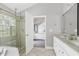 Bright bathroom featuring a double vanity, glass enclosed shower, and doorway to the bedroom at 9508 Vira Dr, Raleigh, NC 27617