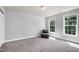 Bright bedroom with two large windows, neutral carpet and walls, a sliding door closet and a chair at 9508 Vira Dr, Raleigh, NC 27617