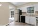 Galley kitchen with stainless steel refrigerator, black dishwasher, white cabinets and double basin sink at 101 Atchison St, Garner, NC 27529