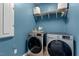 Laundry room featuring shelving, blue wall paint, and modern front-loading appliances at 1021 Sweet Cream Ct, Durham, NC 27703