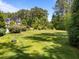 This expansive front yard features lush green grass, mature trees, and a multi-story home with a blue sky backdrop at 1037 Lila Ln, Raleigh, NC 27614