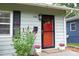 Charming home featuring a vibrant red front door, black shutters, and beautiful landscaping at 106 Eugene St, Carrboro, NC 27510