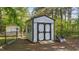 A white storage shed with black trim and a double door in a fenced backyard at 106 Wolverton Dr, Clayton, NC 27527