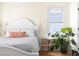 Bedroom features a bed with white bedding, a plant stand, and a bright window providing natural light at 117 Idlewild Ave, Raleigh, NC 27601