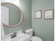 Half bathroom features a round mirror, white vanity, and fresh paint at 120 Avent Pines Ln, Holly Springs, NC 27540