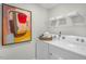 Laundry room includes modern appliances, decorative artwork, and convenient shelving for storage at 1205 Pavo Path, Wendell, NC 27591