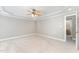 Bright, neutral bedroom includes a ceiling fan, plush carpet, and access to ensuite bathroom at 1221 Tartarian Trl, Apex, NC 27502