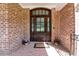 Inviting brick front porch with a dark wood door, glass panels, and potted flowers at 12508 Angel Falls Rd, Raleigh, NC 27614