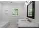 Modern bathroom featuring white tile, marble counters, and a large framed mirror, offering a clean and elegant design at 1314 Hudson Ave, Durham, NC 27705