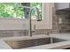 A kitchen sink with stainless steel faucet sits beneath a window overlooking lush greenery at 1314 Hudson Ave, Durham, NC 27705