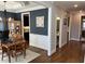 Open dining area features wood floors, wainscoting, and a decorative chandelier, next to the kitchen and hall at 145 Plantation Dr, Youngsville, NC 27596