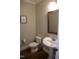 Powder room featuring pedestal sink, framed mirror, and dark hardwood floors at 145 Plantation Dr, Youngsville, NC 27596