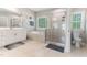 Bright bathroom features a glass enclosed shower, a soaking tub, dual vanities, and tile flooring throughout at 1520 Banks Brooke Dr, Raleigh, NC 27603