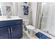Bathroom featuring blue vanity, white toilet, shower, and decorative wall art at 1520 Banks Brooke Dr, Raleigh, NC 27603