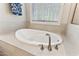 Close up of bathroom soaking tub, faucet, and window with bright natural light streaming in at 1520 Banks Brooke Dr, Raleigh, NC 27603