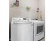 Laundry room with white, front load washing machine and dryer with wire rack above at 1520 Banks Brooke Dr, Raleigh, NC 27603