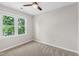 Neutral bedroom featuring carpet, ceiling fan, and a large window with an outside view at 2 Great Oak Ct, Durham, NC 27713