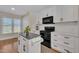 Well-lit kitchen features white cabinets, modern appliances, and island with a dark stone countertop at 2006 Woodstone Dr, Archer Lodge, NC 27527