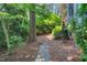 Lush backyard with a stone pathway, mature trees, and shrubbery at 2018 Waterton Ln, Apex, NC 27502