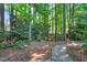 The backyard features a serene setting with mature trees, stone pathway, and a charming bench at 2018 Waterton Ln, Apex, NC 27502