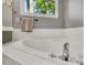 Bright bathroom featuring a soaking tub with tile surround and a window overlooking a wooded area at 2018 Waterton Ln, Apex, NC 27502