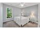 Bedroom with a metal frame bed, ceiling fan, carpet and a large window overlooking trees at 2018 Waterton Ln, Apex, NC 27502