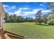 Spacious backyard with lush green grass and mature trees and stairs leading to the porch at 202 Reeder Branch Dr, Clayton, NC 27520