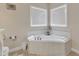 Bathroom showcasing a tiled corner bathtub, toilet, and ample natural light at 202 Reeder Branch Dr, Clayton, NC 27520