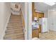 View of carpeted staircase adjacent to a kitchen with wooden cabinets and white appliances at 202 Reeder Branch Dr, Clayton, NC 27520