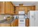 Well-lit kitchen boasts wooden cabinetry, sleek countertops, and white appliances at 202 Reeder Branch Dr, Clayton, NC 27520