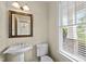 Bright half-bathroom featuring pedestal sink, toilet, and window offering natural light at 208 Willowbend Ln, Hillsborough, NC 27278