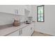 Functional laundry room with white cabinetry, gray countertops, sink, and a window at 2104 Manuel St, Raleigh, NC 27612
