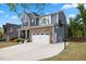 Two-story home exterior with a stone facade, well-kept lawn, and a basketball hoop on the driveway at 221 Obsidian Dr, Holly Springs, NC 27540