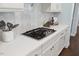 Kitchen counter with stainless steel cooktop, modern white cabinets, marble backsplash, and hardware at 221 Obsidian Dr, Holly Springs, NC 27540