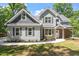 Inviting two-story home showcasing gray siding and stone accents, framed by lush greenery and a welcoming walkway at 2405 Pearces Rd, Zebulon, NC 27597