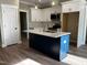 Modern kitchen featuring white cabinets, navy blue island, stainless steel appliances, and stone countertops at 2405 Pearces Rd, Zebulon, NC 27597