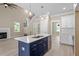 Open-concept kitchen showcasing a blue island, white cabinets, and modern fixtures, seamlessly flowing into the living area at 2405 Pearces Rd, Zebulon, NC 27597
