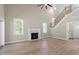 Spacious living room with a fireplace, tall windows, and an open staircase, creating a bright and airy atmosphere at 2405 Pearces Rd, Zebulon, NC 27597
