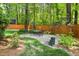 Landscaped backyard featuring a gravel patio with dining set, fenced perimeter, and mature trees at 2481 Foxwood Dr, Chapel Hill, NC 27514