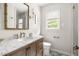 A stylish bathroom with marble countertops, wood cabinets, and a window with bright light at 2481 Foxwood Dr, Chapel Hill, NC 27514