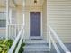 Inviting entryway featuring a raised porch with stairs, white railings, and a dark-colored front door at 2600 Newbold St, Raleigh, NC 27603