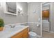 Clean bathroom with a wooden vanity, toilet, and access to a laundry area at 2614 Cambridge Rd, Burlington, NC 27215