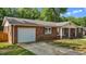 Brick home with attached garage, manicured lawn, and a covered porch with a charming porch swing at 2614 Cambridge Rd, Burlington, NC 27215
