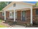 Charming front porch with brick columns, a porch swing, and decorative front door at 2614 Cambridge Rd, Burlington, NC 27215