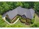 Aerial view of a brick home with a dark roof surrounded by mature trees in a wooded neighborhood at 27 Woodgate Ct, Durham, NC 27713