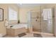 Bright bathroom features a soaking tub, glass enclosed shower and neutral toned tile at 27 Woodgate Ct, Durham, NC 27713